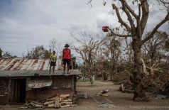Criança e idoso sobem no telhado de uma casa danificada após passagem de ciclone por Vanuatu, na Oceania, em m... (Unicef)