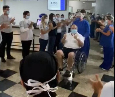 Funcionários alinhados no corredor, batendo palmas, enquanto o paciente passa em uma cadeira de rodas. Foto: reprodução/vídeo