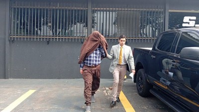 Paulo Lange, ao lado de seu advogado, deixa sede do SIG escondendo o rosto (Foto: Leandro Holsbach)