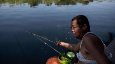 Chinês pesca com a camiseta enrolada até o peito: agora está proibido Foto: AFP