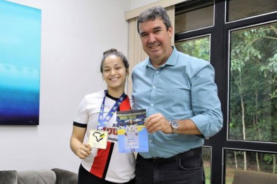 Ana Demarco com a medalha nas mãos ao lado do governador Eduardo Riedel, que ganhou uma foto autografada de presente da judocae (Foto: Saul Schramm/Divulgação)