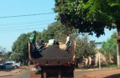 Trabalhadores que fazem tapa-buraco são transportados em carroceria, em meio ao material usado para consertar... (Divulgação)
