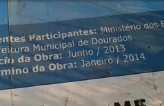 Caída no meio do mato, placa instalada pela Prefeitura de Dourados diz que a obra deveria estar pronta há um a... (Reprodução)