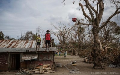 Criança e idoso sobem no telhado de uma casa danificada após passagem de ciclone por Vanuatu, na Oceania, em m... (Unicef)