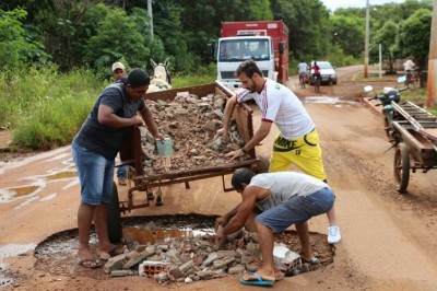 Homens jogam entulhos na tentativa de improvisar um tapa-buracos em trecho da Via Parque (Eliel Oliveira)
